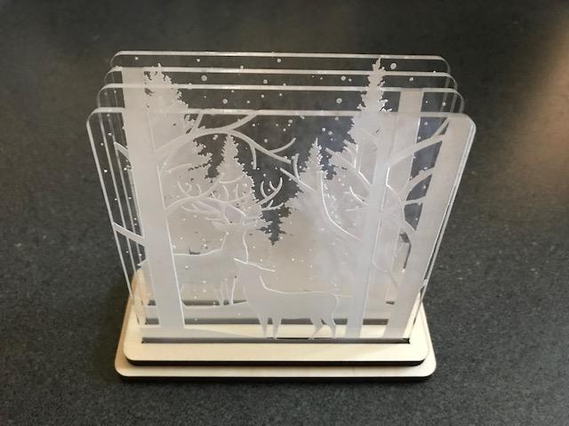 Clear layered coasters with winter trees held in a wooden base