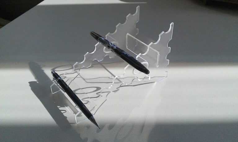 Clear acrylic butterfly pen holder supporting a black pen on a display base