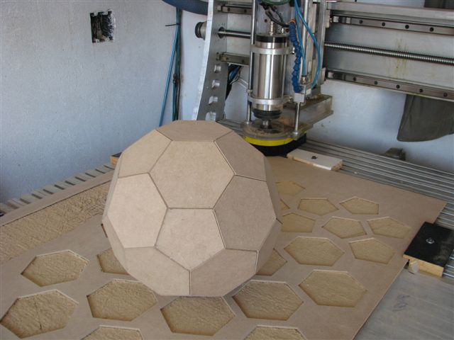 Faceted wooden soccer ball model beside CNC cut panels