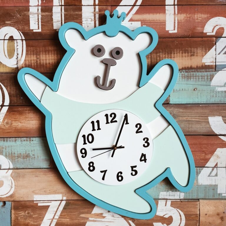 Turquoise and white bear-shaped wall clock with a small crown and a numbered belly dial