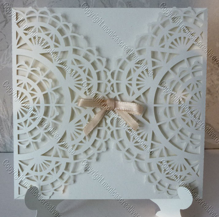 White gatefold card with overlapping circular lace patterns and a ribbon bow