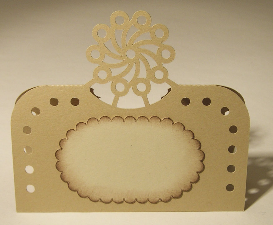 Gold place card with a curled floral crest and dotted border