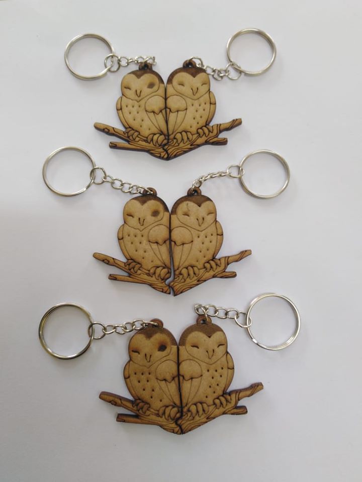 Three examples of paired owl keychains perched together on a branch